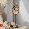 Gold finish vintage pedestal photo frame on a tabletop